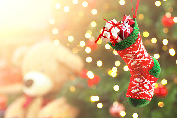 Little christmas stocking full of gifts on christmas tree background.